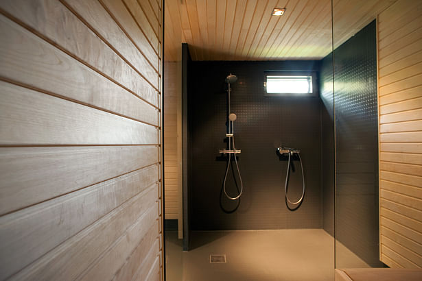 The wash room continues on the theme of restrained materials. Only wood paneling and grey rubber flooring are used. Photo by Arno de la Chapelle.