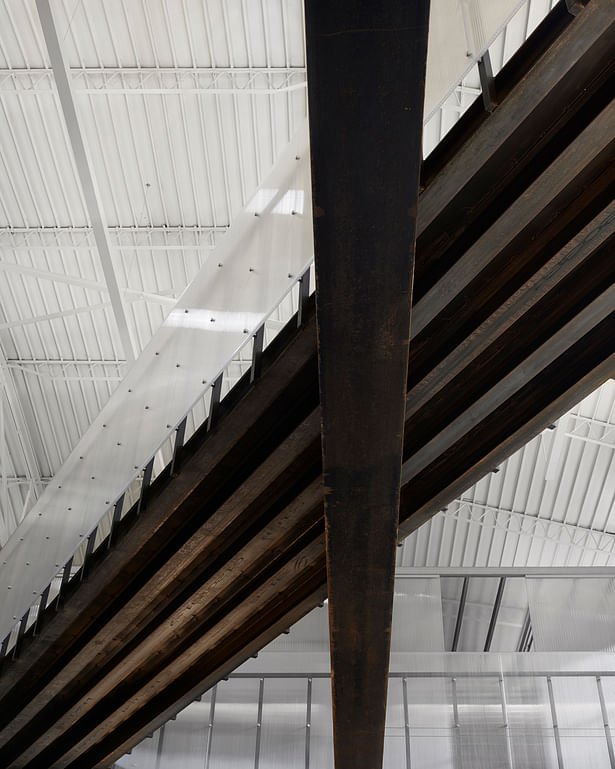 View from below of the new steel bridge and historic wide flange beam. We left the steel exposed and waxed it to keep it from rusting. The 1930s bowstring truss ceiling and deck is visible.
