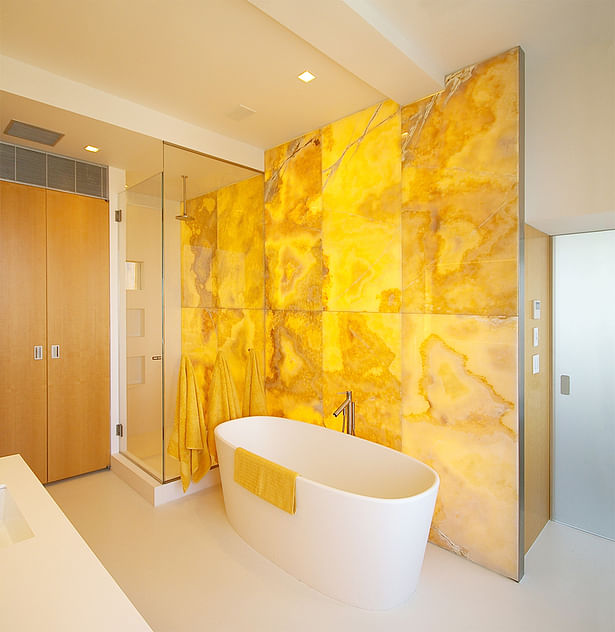 Glowing onyx wall warms the master bathroom