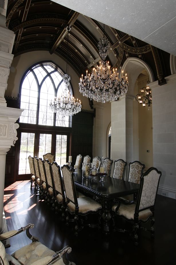 This grand dining area is complimented by beautiful chandeliers, high arched Gothic-style window and hand-carved stone fireplace and surround.