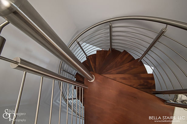 Curved stainless steel rod railings were installed with a top mounted stainless steel handrail throughout the staircase.