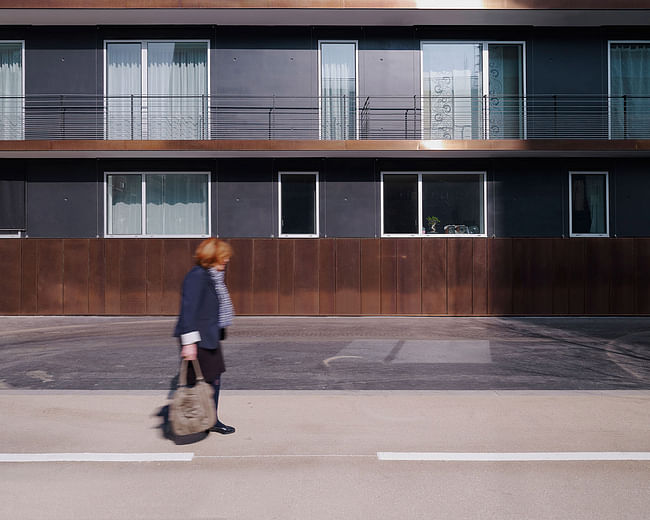 Details: 'Where the building is anchored to the ground, a copper skirt runs along the building, and is given visual correspondance to the balcony strips above.' (Photo: Julien Lanoo)