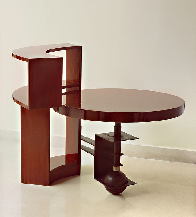 Table and bookcase (MB960), c. 1930, designed by Pierre Chareau, walnut and black patinated wrought iron; Bookcase: 36 1⁄2 × 45 1⁄4 × 8 in. (92.7 × 114.9 × 20.3 cm); table: 23 1⁄2 in. (59.7 cm) high, 33 3⁄4 in. (85.7 cm) in diameter. Vallois, Paris. Photograph by Ken Collins, image provided by Gallery Vallois America, LLC