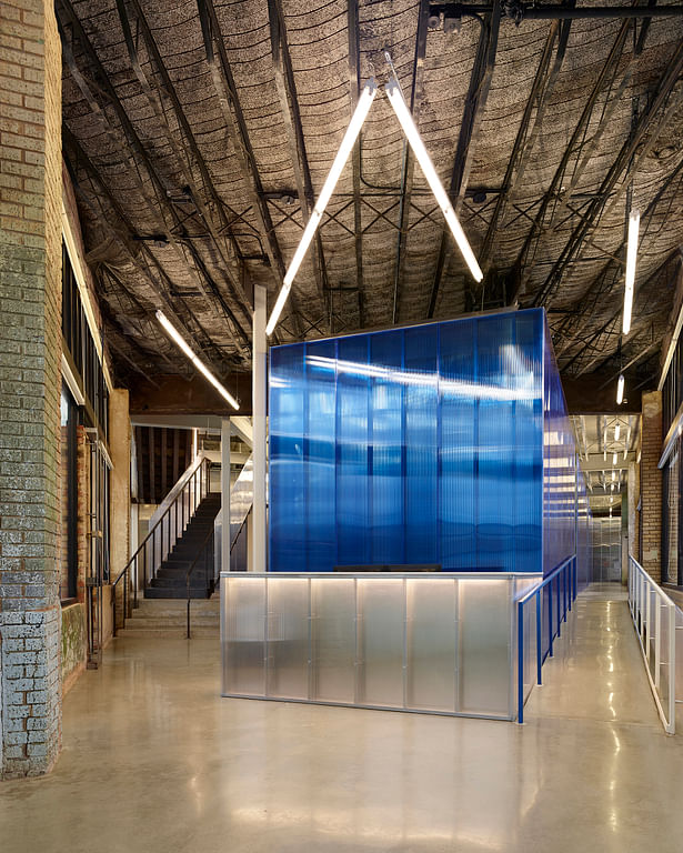 View from the flatiron entry towards the reception desk. The blue polycarbonate office core defines new vs. historic. The original exposed metal lath and concrete deck above remains. Floors are polished concrete. 