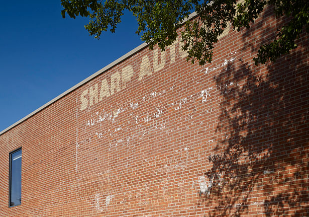 Partial west elevation showing the original ghost sign still in place. New windows were added on the east and west which were surfaces that were once adjacent buildings. 