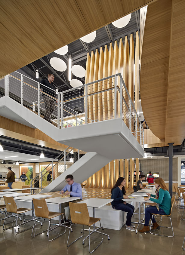 Vertical open stair and wood sculpture connects the two level dining hall.