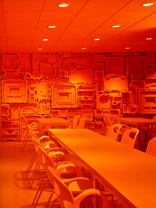 In the café, repurposed formed foam packaging becomes a sculptural wall finish and a statement on the company’s commitment to reducing waste. Orange is a new corporate color brought in to give life to their branding. 