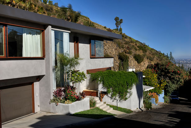 The house, sited on an oddly shaped hillside lot, was reorganized and refocused to take advantage of the views. The new street-side addition includes two upstairs bedrooms, with large windows, and a 16-foot-tall wrap-around glass window wall, or 'jewel box,' next to the front door.