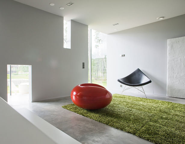 The living room and kitchen are separated from the staircase by a massive wall, which affords views through the immaterial glass wall behind. Photo by Arno de la Chapelle.