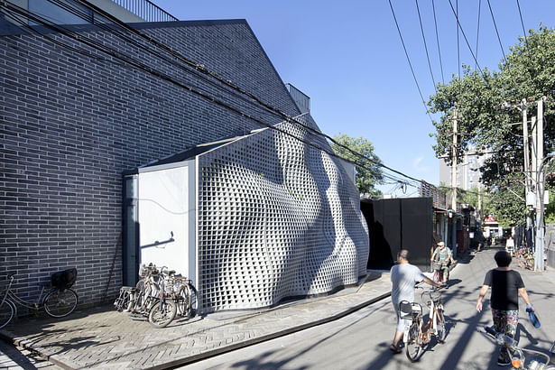 The façade enters the space of the hutong as a flowing fabric