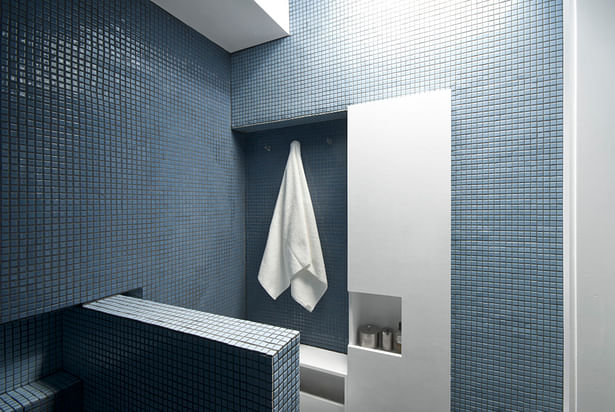 The bathroom, capped by a skylight, is a luminous blue gem 