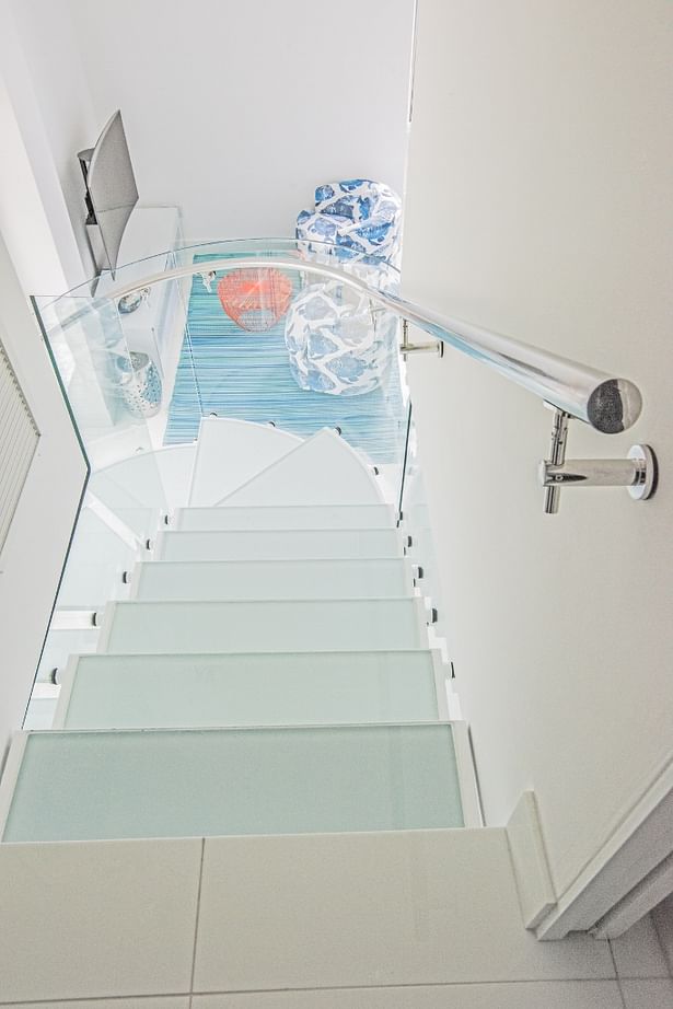 View descending from the second floor features a curved chrome stainless steel handrail to accompany the curved glass panels below.