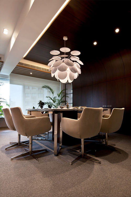 Meeting room Epsylon where a storage wall with hidden flat screen turns into a ceiling panel. The white shells of the Marset designer light contrast with the dark veneer ceiling.