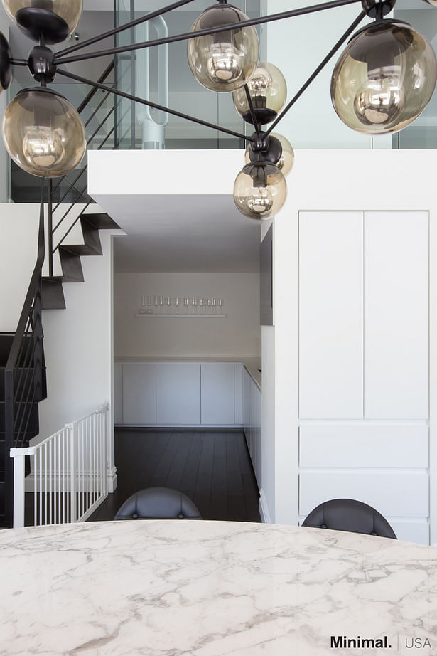 Moving to the left, passing the modern living room, there is the kitchen's entrance with an adjacent pantry cleverly embedded in the wall, becoming an integral part of the column.