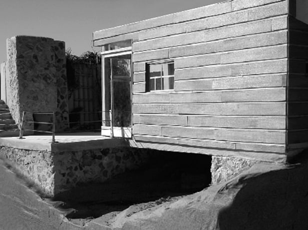 Shown is the prominent exterior fireplace and the southeast front face of the building, which features the wooden slat exterior. 