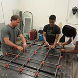 Studio H volunteer Eric Wandmacher and Studio H students Kerron Hayes and Alexia Williams construct a portion of the base for the Windsor Farmers Market pavilion. From IF YOU BUILD IT, a Long Shot Factory Release 2013.