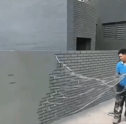 Shane Reiner-Roth (<a href="https://www.instagram.com/p/CQq6o8VAmNB/">@everyverything</a>), Still from a video of a man working on a faux-brick wall, United States, June 28, 2021. Source: Instagram © Shane Reiner-Roth.