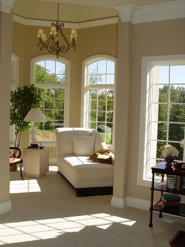 The sitting room offers ample natural light with several arched windows and high ceiling.