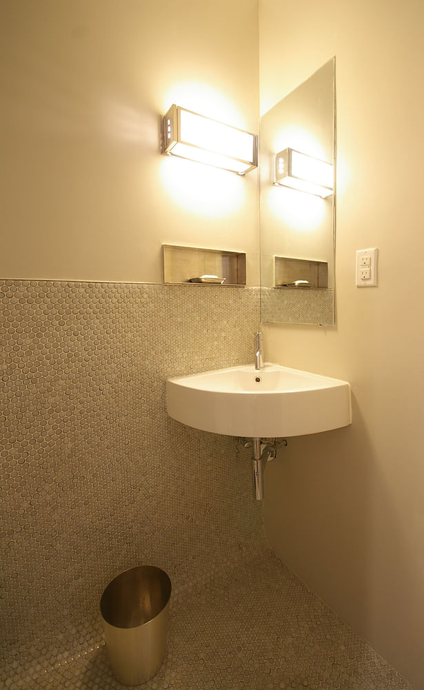 Small powder room exploits the tiny scale of penny tiles at floor and wainscott