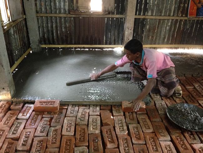 A member of the community lending a hand and smoothing his new concrete floor. Image courtesy of ARCHIVE.