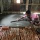 A member of the community lending a hand and smoothing his new concrete floor. Image courtesy of ARCHIVE.