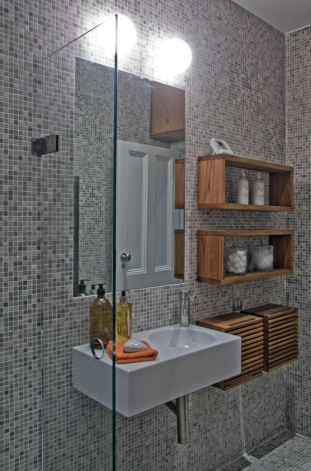 Guest shower room with tumbled marble mosaics and bespoke teak cabinets