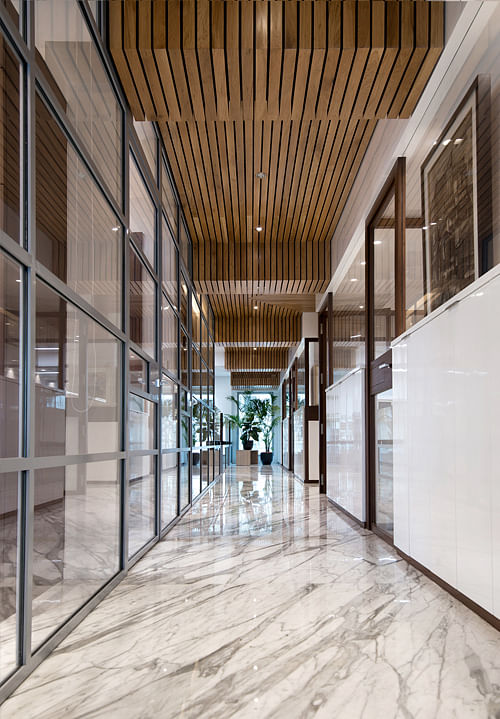 Passage between the meeting rooms on the left and the cabins on the right with custom made wooden ceiling and steel facade. The Statuario marble continues one foot inside the meeting rooms to create a soft transition effect. 