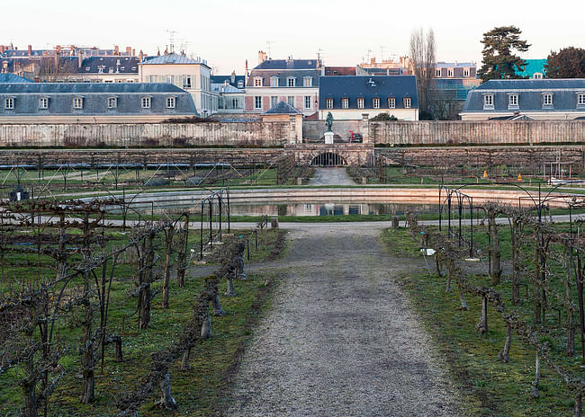 Potager Du Roi, in Versailles, France. View across the central fountain in the Grand Carré towards the north, with a statue of Jean-Baptiste de La Quintinie and the cityscape beyond, 2015. Photo: Alexandre Petzold