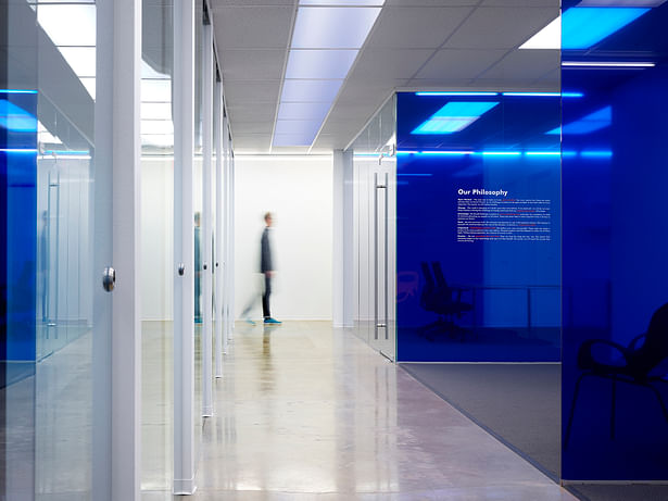 Administrative offices and team break-out rooms populate a blue glass gallery that displays the company’s history, mission, and business philosophy.