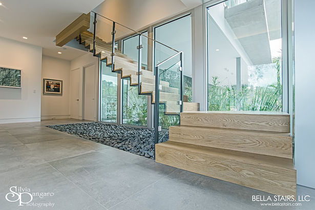 Featuring a Floating Custom Painted Steel Center-beam, White Oak Wood Treads with Closed Risers, and Laminated Glass Inlay Railings.