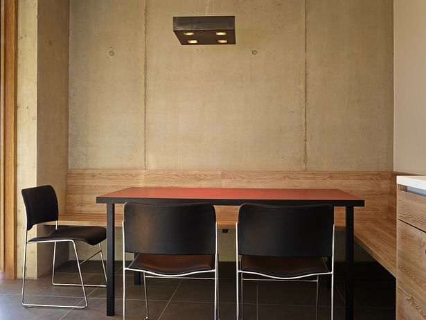 The red tabletop and the concrete wall provide accents inside the kitchen.